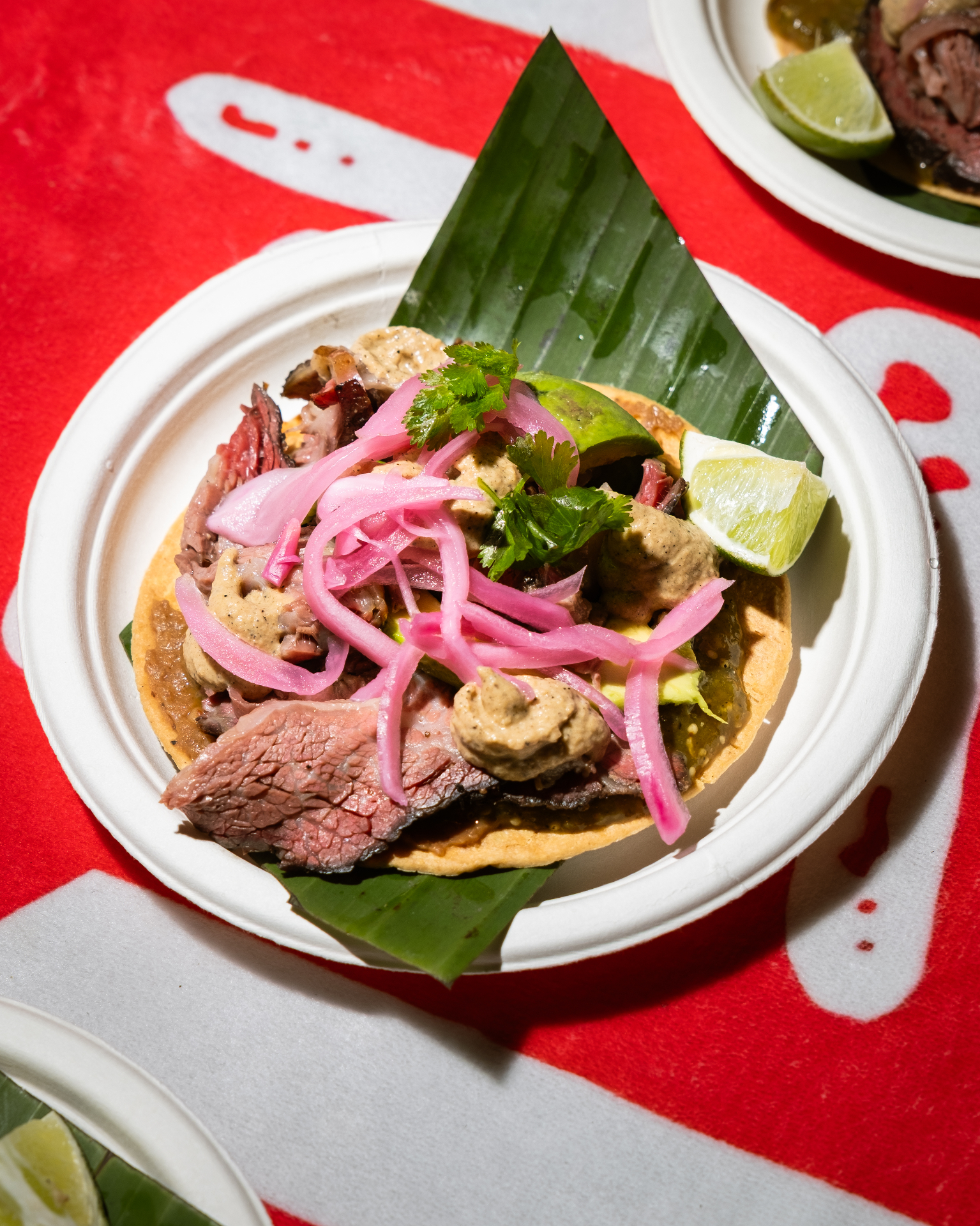 Brisket taco on banana leaf over red branded paper