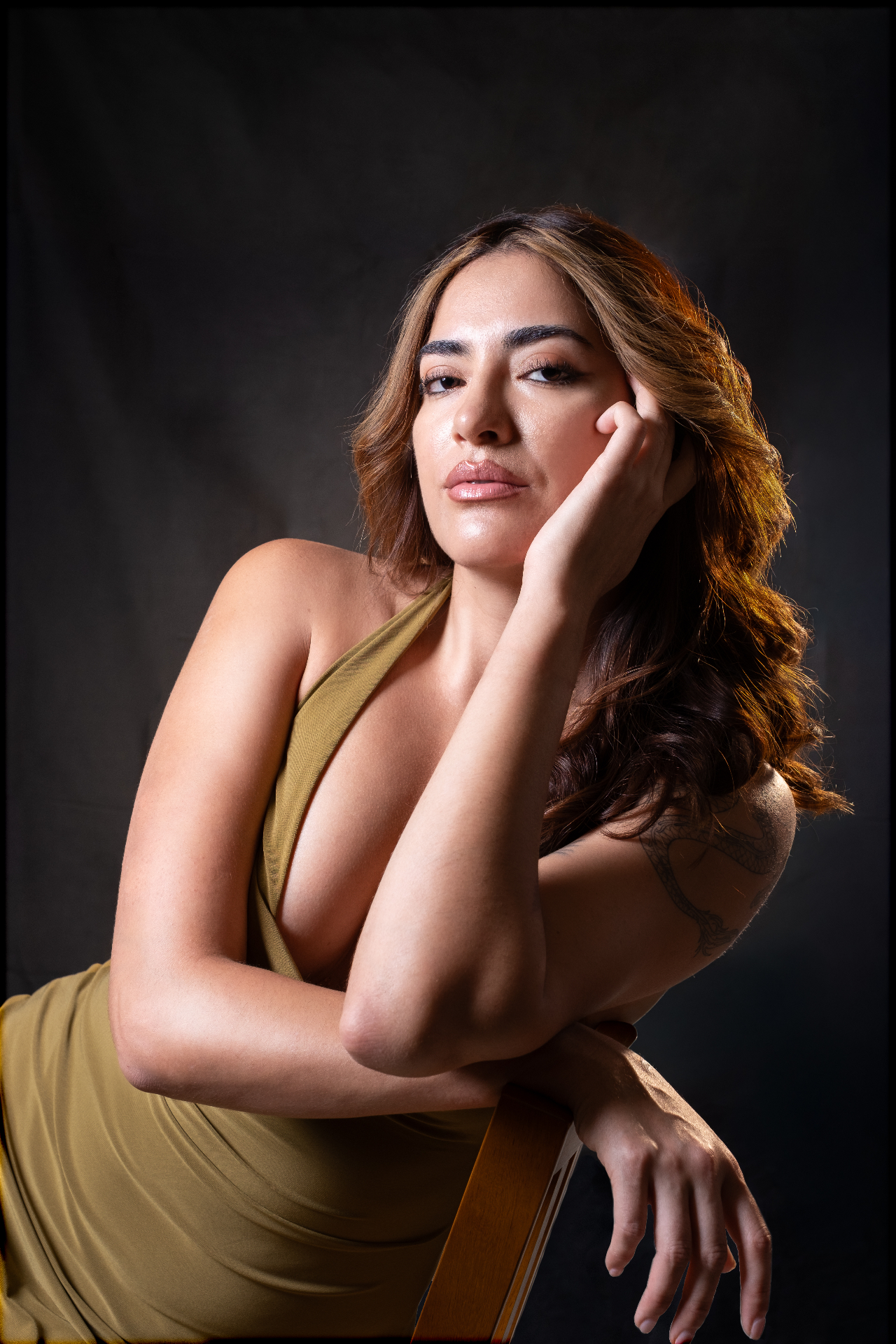 Editorial portrait in olive dress against a dark backdrop